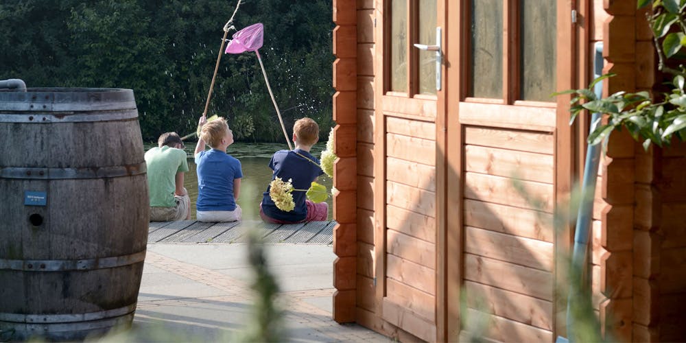 tre barn som fisker med hov ved et anneks