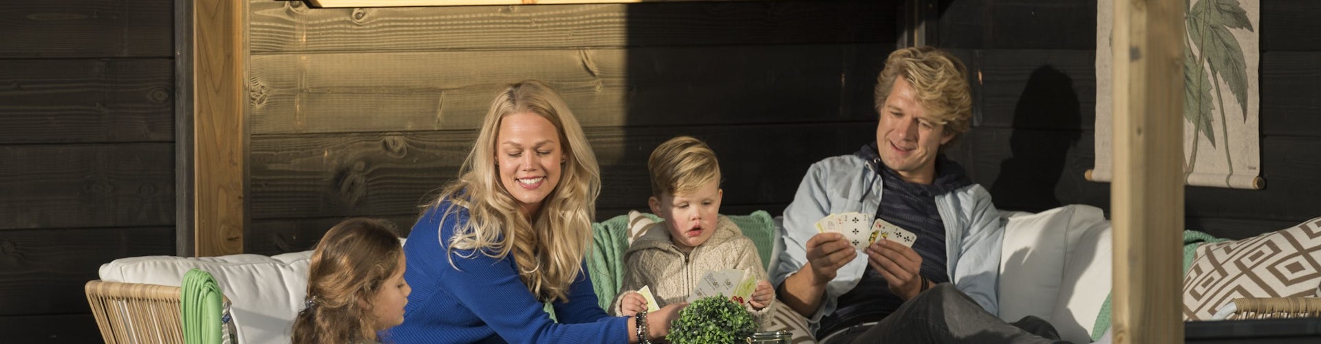 Utestuehygge Familie som hygger seg med ortspill i sofa ute under tak