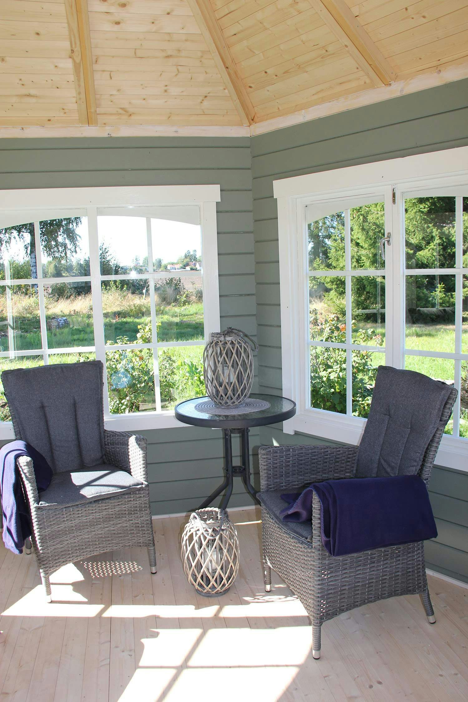 Lysthus grønnmalt inne med to stoler og bord