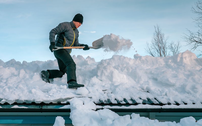 snømåking mann som måker snø av tak