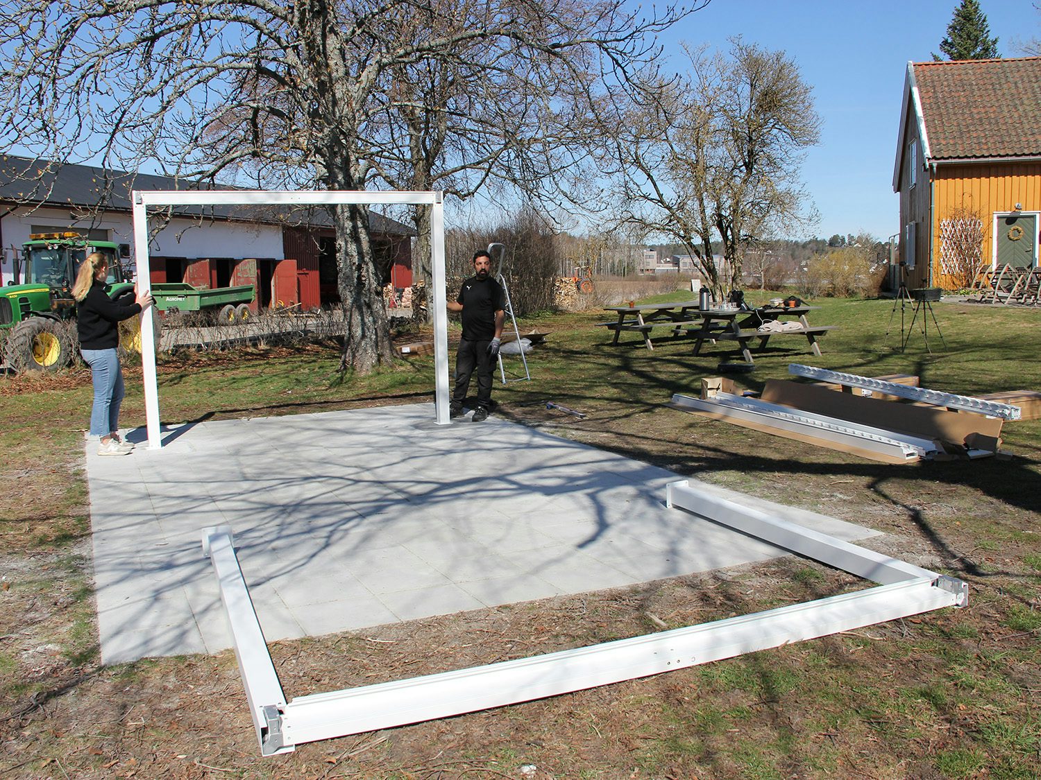 mann som holder oppe en del av pergola og den andre ligger på bakken. Foto