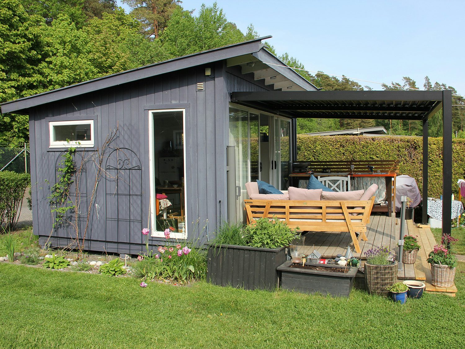 Vegghengt pergola sett fra siden på grått lite hus