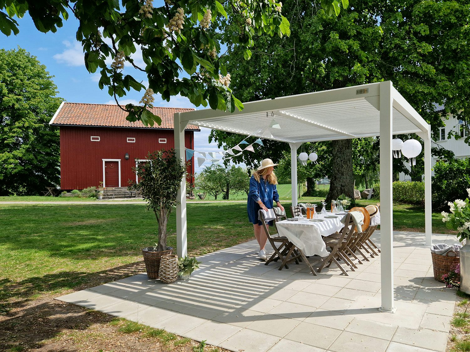 dame med hatt som dekker bord under pergola