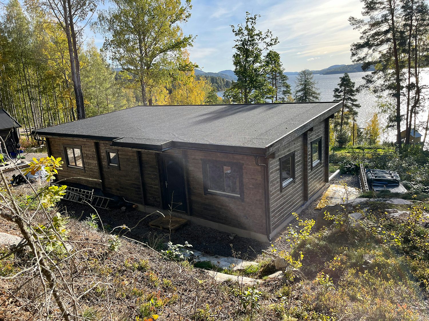 Brun hytte fra baksiden med utsikt over sjø