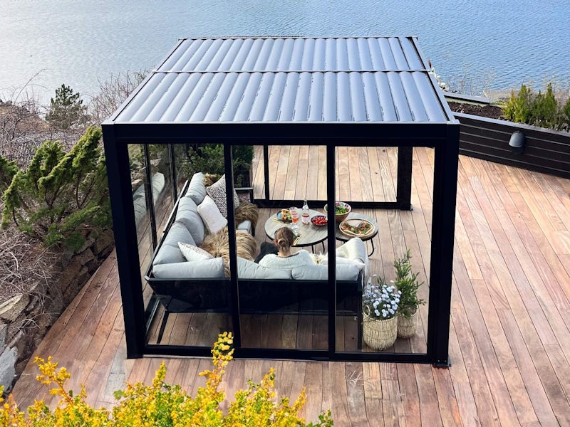 Pergola dører (Tilpasset) sort pergola med skyvedører i glass på en platting med utsikt ut over havet