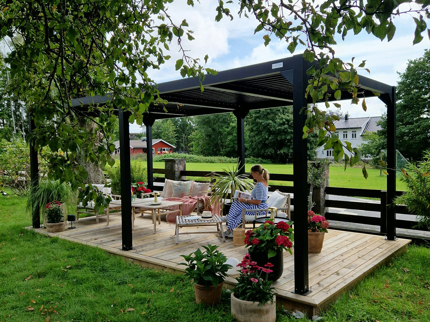 Dame som leser blad under sort pergola. Foto
