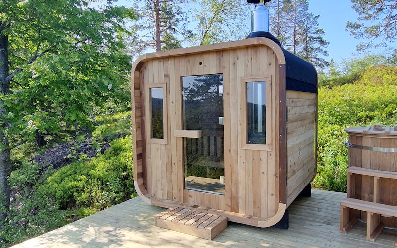 Badstu1 4_3 Sauna med vinduer i front på platting i skog.foto
